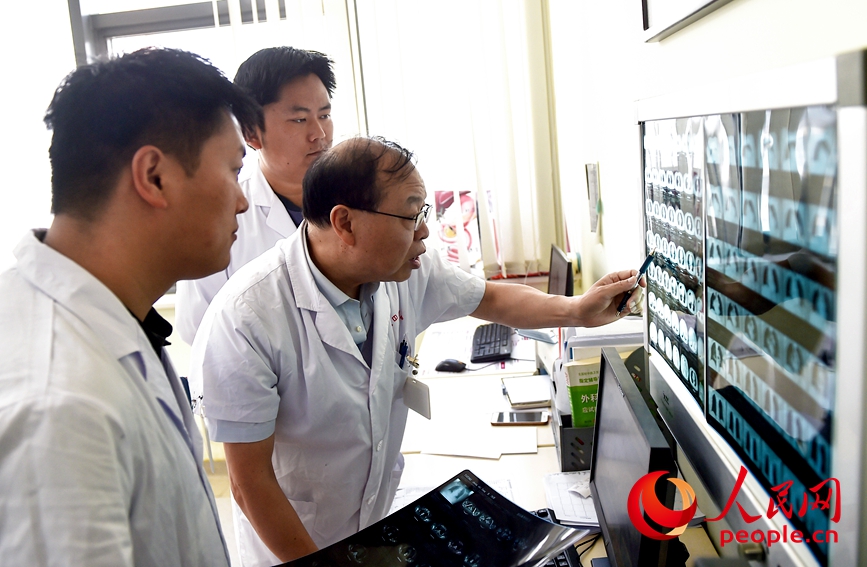 河南科技大学第七附属医院，几名医护人员坚守岗位讨论研究患者病情。人民网记者 尚明桢摄