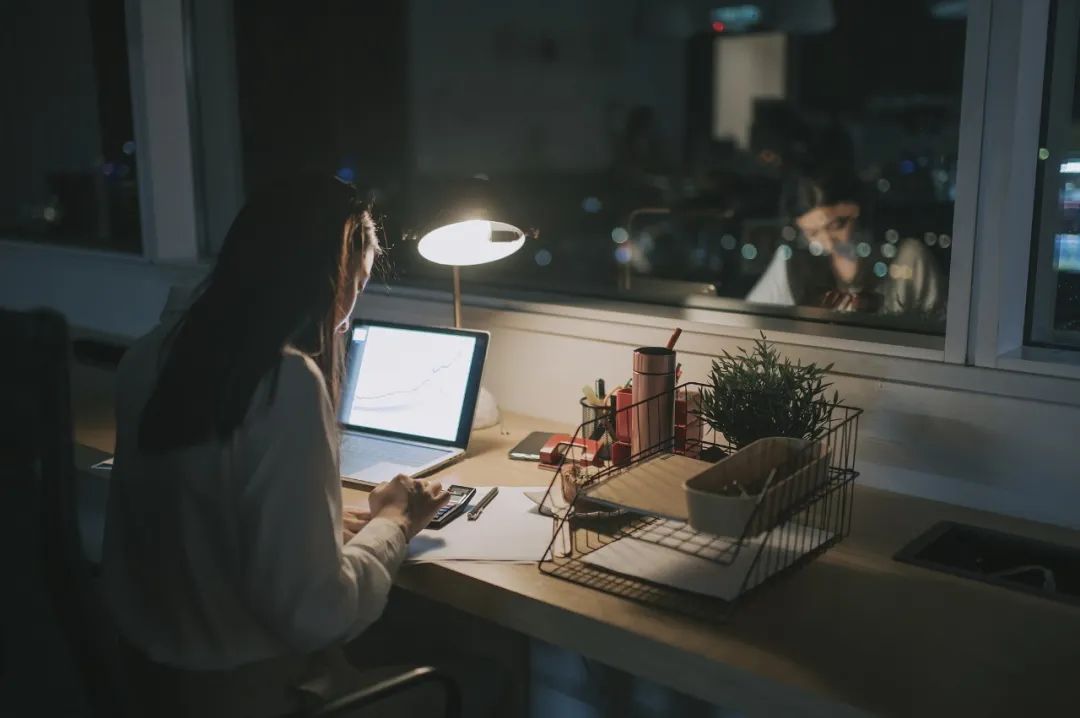 亚洲华裔女白领在办公室工作到深夜独自赶财务报告图片素材