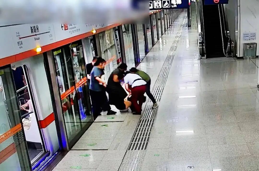 工作人员和热心乘客合力将发病乘客抬下车.jpg