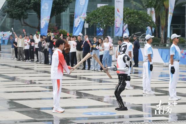 11月2日，第十五届全国运动会深圳站火炬传递活动现场，“0号”火炬手人形机器人“夸父”向“手搓火箭”高中生王裕宁传递火炬。