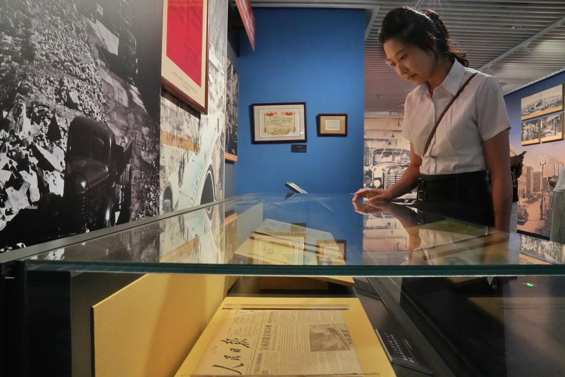 一名观众在展区内观看1956年《人民日报》关于解放牌卡车试制成功的报道。人民网记者 李洋摄