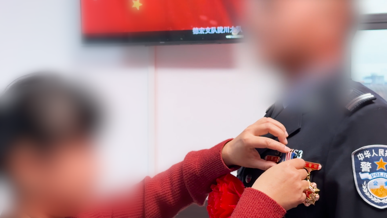 诚警官妻子在年度表彰大会上为丈夫佩戴勋章。